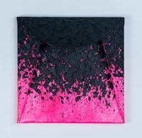 a black and pink envelope on a white surface